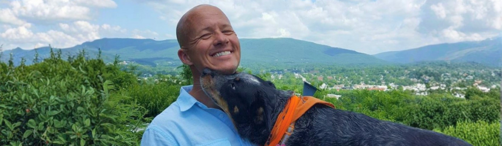 Holistic veterinarian Dr. Matt Parker smiling with his dog outdoors, reflecting his personal approach to holistic veterinary care